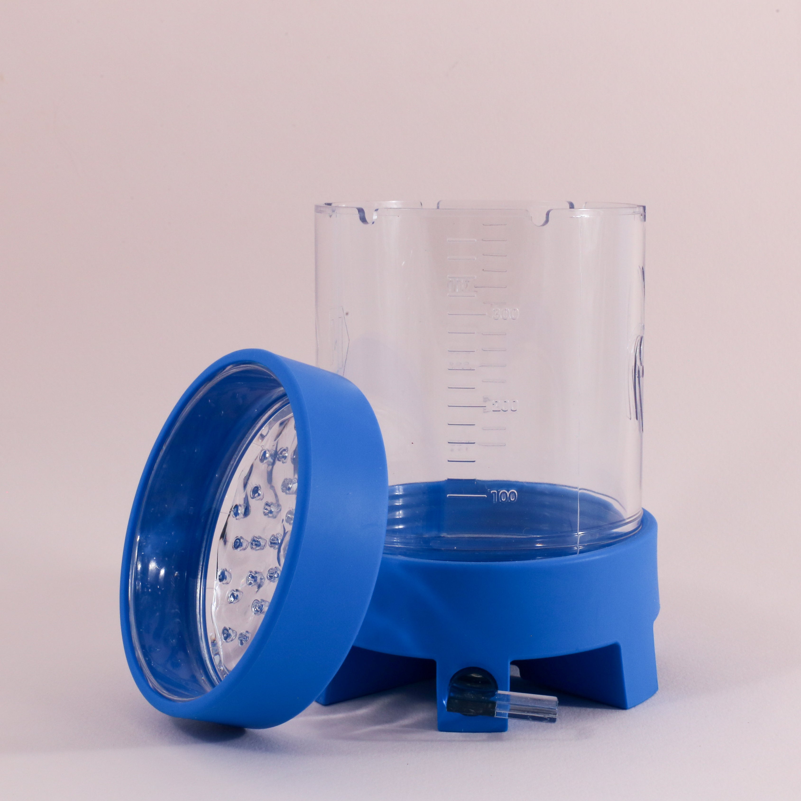 The NextLevel Pulsar Brewer by vendor-unknown is a transparent plastic container with measurement markings, a blue lid with holes, and a blue base featuring an adjustable flow valve, shown against a light background.