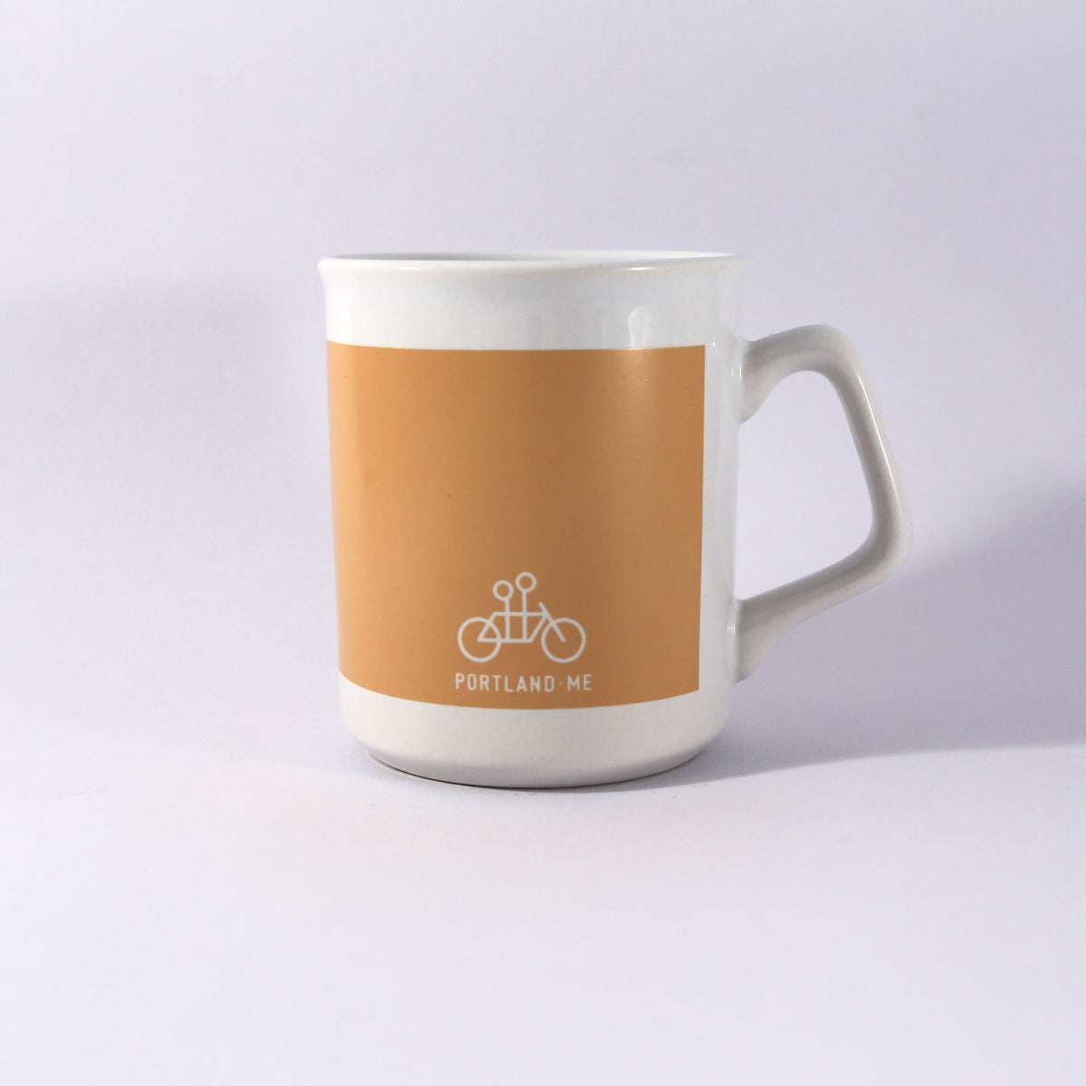 A Kathy Heideman Spread Joy Mug by Tandem Coffee Roasters with a beige top, white bottom, and a bicycle logo marked "Portland - ME" on a light gray background. Handwash recommended.