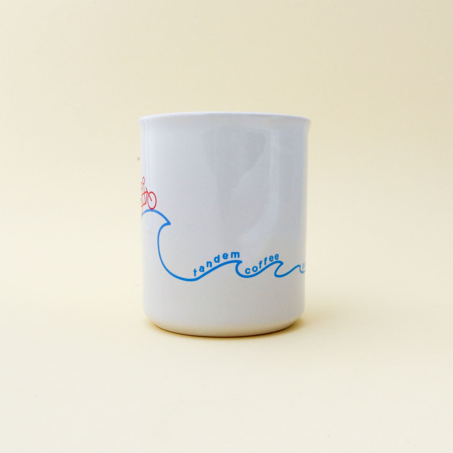 A white Sunshine Mug with a blue "Tandem Coffee Roasters" logo and red detailing, set against a plain, light beige background.