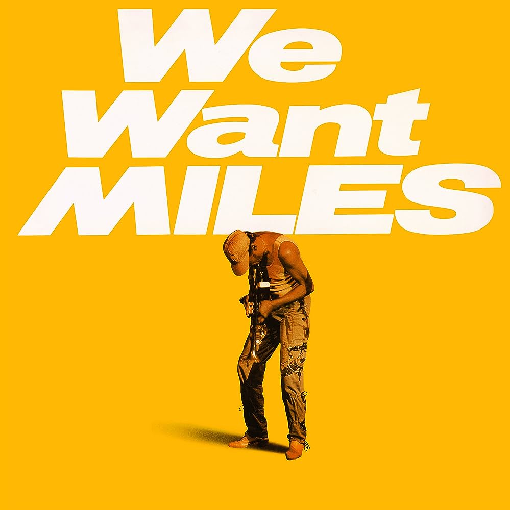 A bold graphic featuring the phrase "Miles Davis - We Want Miles" in large white letters on a bright yellow background, with a stylized image of Miles Davis holding a trumpet, bending forward slightly by Tandem Coffee Roasters.