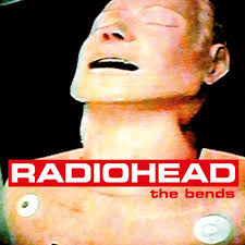 Close-up of a mannequin’s head and upper torso with eyes closed, mouth slightly open. Radiohead - The Bends and Tandem Coffee Roasters appear in bold red and white text across the image.
