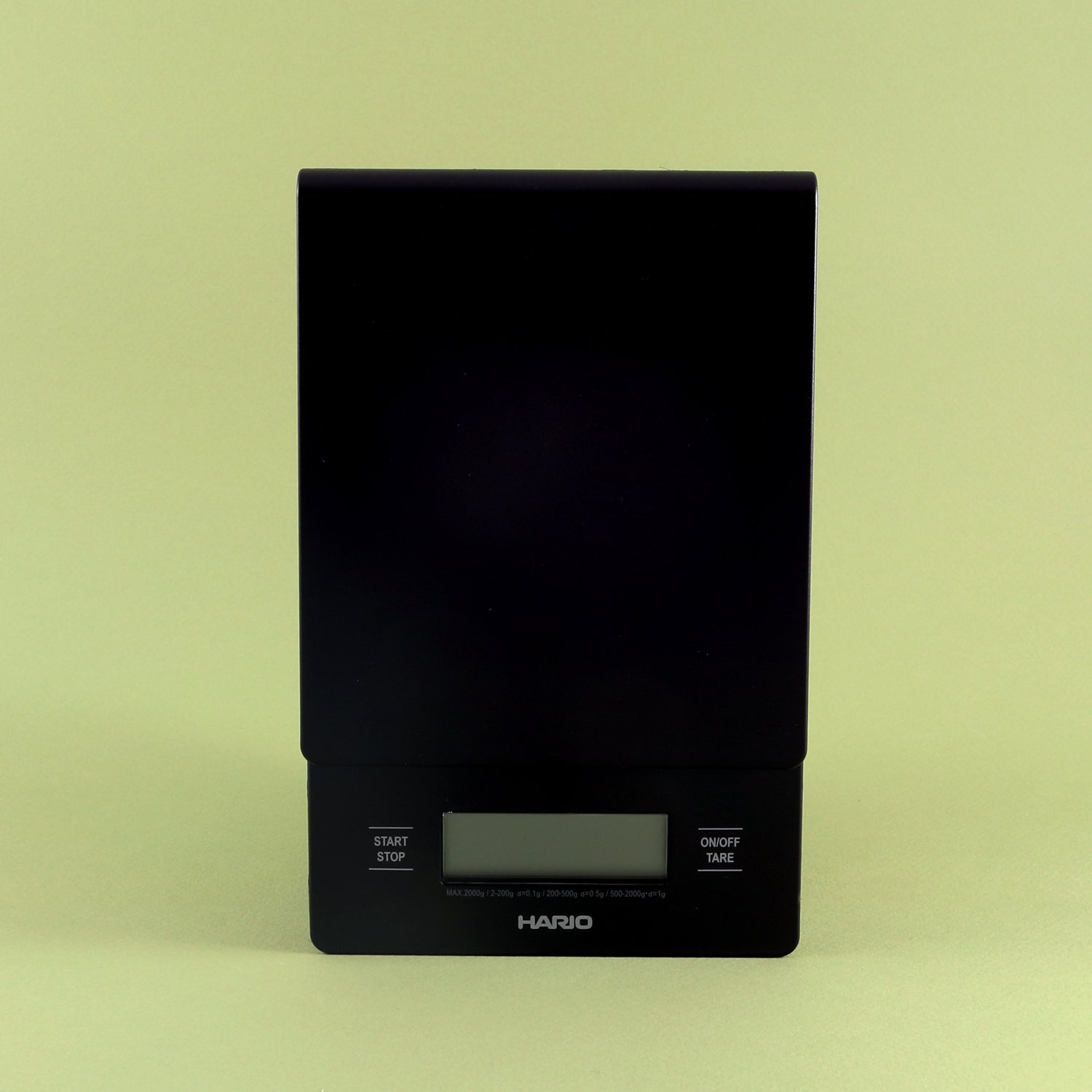 A black Tandem V60 Drip Scale with digital display, centered on a pale green background. The scale features buttons for start, stop, and tare functions.