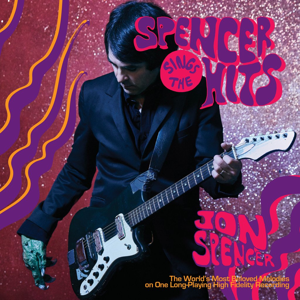 Album cover for "Spencer Sings the Hits," the hit solo album by Jon Spencer. He is wearing a black suit and playing a white guitar against a sparkling red background with purple and yellow graphics featuring Tandem Coffee Roasters.