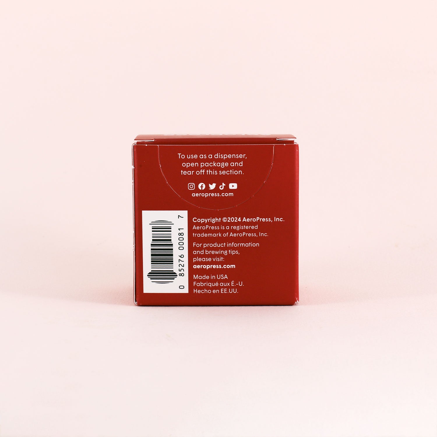 A red Tandem Aeropress Filters box is shown from the back with white instructions, barcode, copyright, and website text—highlighting the 350-count filters—displayed on a light pink background.