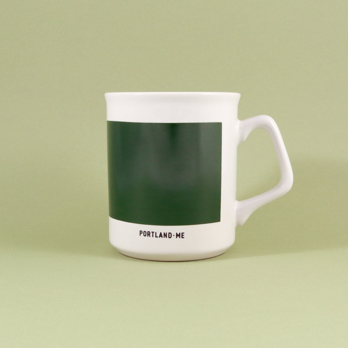 A Maine Mug with a green color block and the text "portland-me" at the bottom, against a light green background by Tandem Coffee Roasters.