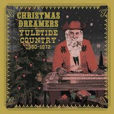 The album, "Christmas Dreamers - Yuletide Country 1960 - 1972," by Tandem Coffee Roasters, features a Santa Claus figure dressed in red playing a musical instrument. The cover is adorned with a decorated Christmas tree, starry night sky, and a tracklist of classic Christmas music.
