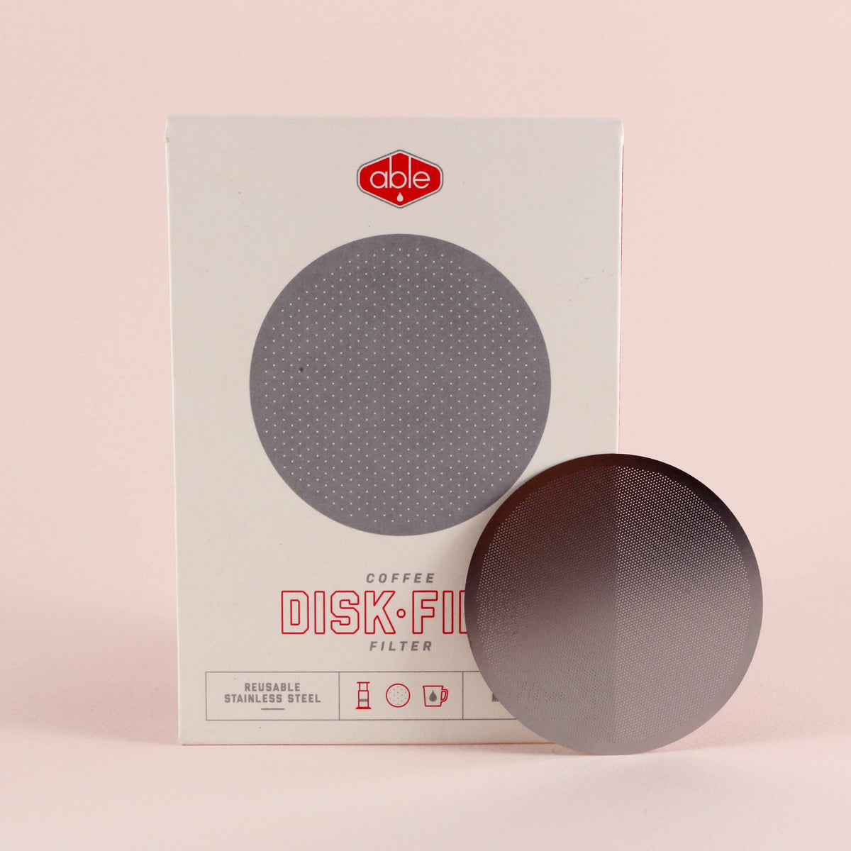 A Tandem Coffee Roasters Able Aeropress Filter Disk (Fine) designed for AeroPress is displayed in front of its packaging, which is labeled "disk fine," against a soft pink background.