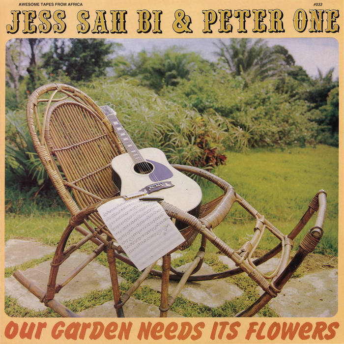 Album cover "Our Garden Needs Its Flowers" by Jess Sah Bi & Peter One, featuring a wicker chair, an acoustic guitar from the Good Thing Selection, and sheet music, set in a lush Tandem Coffee Roasters.