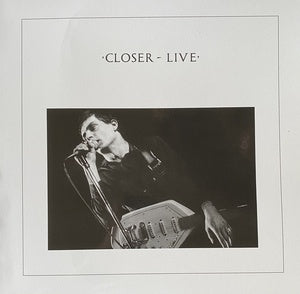 Black and white photo of a man singing into a microphone with an electronic device in front at one of his rawest formats live sets, titled 'Joy Division - Closer - Live'.