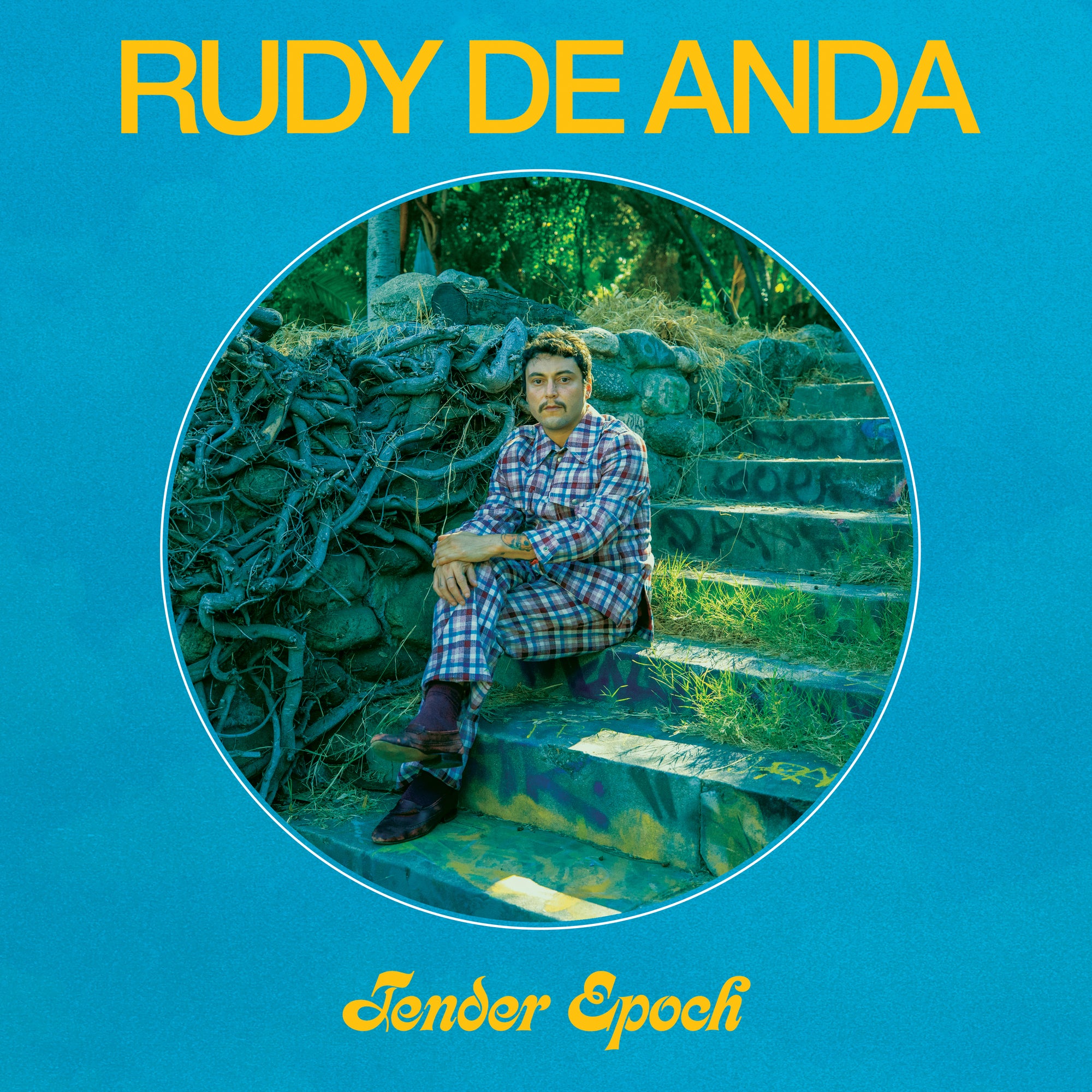 Album cover of "Tender Epoch" by Rudy De Anda. Features Rudy sitting on steps surrounded by greenery, wearing plaid clothing with a reflective expression. (Product Name: Tandem Coffee Roasters - Tender Epoch)