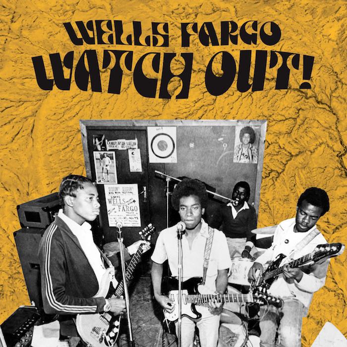 Four musicians play guitars and sing with mics in a cozy room lined with posters and a yellow textured backdrop. Bold above: Wells Fargo - Watch Out! from Tandem Coffee Roasters, channeling classic café music vibes.